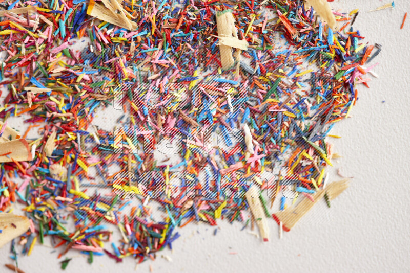 This image showcases a vibrant multicolored pencil shavings scattered on grey background