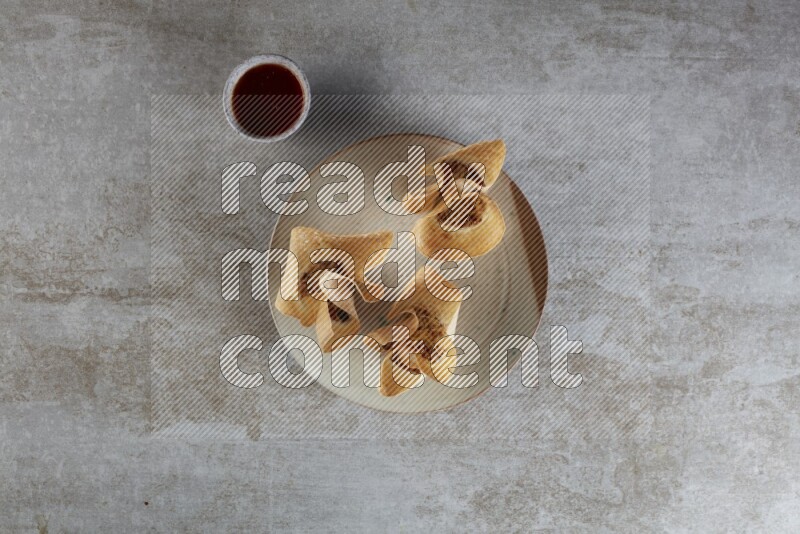 wonton cups with soy sauce ramkin on multi colored pottery on grey textured counter top