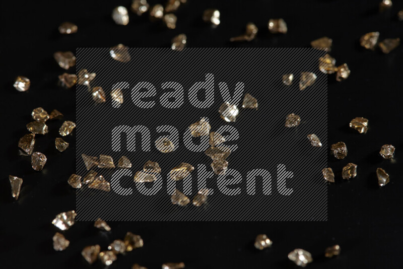 Gold shimmering fragments of glass scattered on a black background