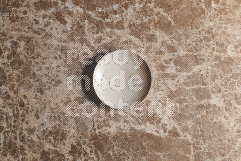 A beige pottery plate on beige marble background
