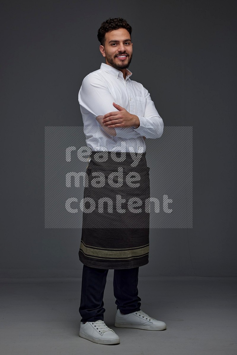 A man wearing smart casual and apron standing and making multi poses eye level on a gray background