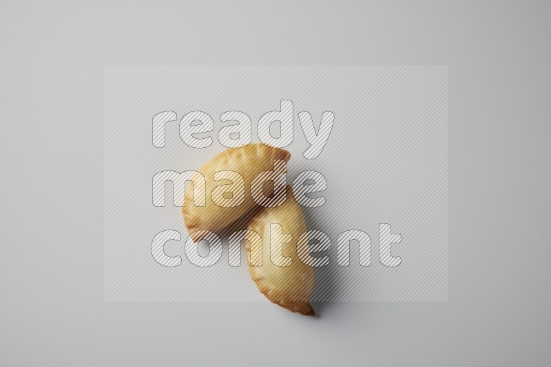 Two fried sambosa from a top angle on a white background