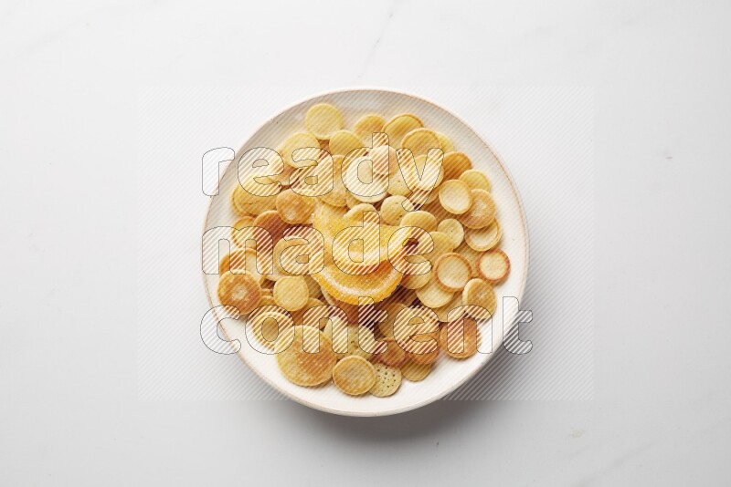 Top-view shot of orange candy cereal pancakes in a round bowl on white background