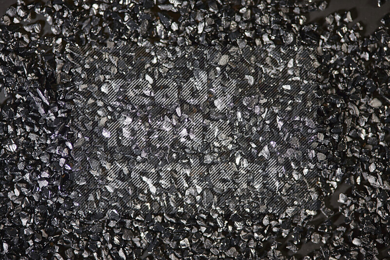 Black shimmering fragments of glass scattered on a black background