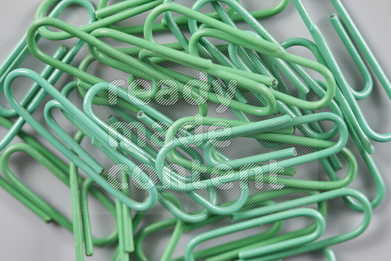 Green paperclips isolated on a grey background