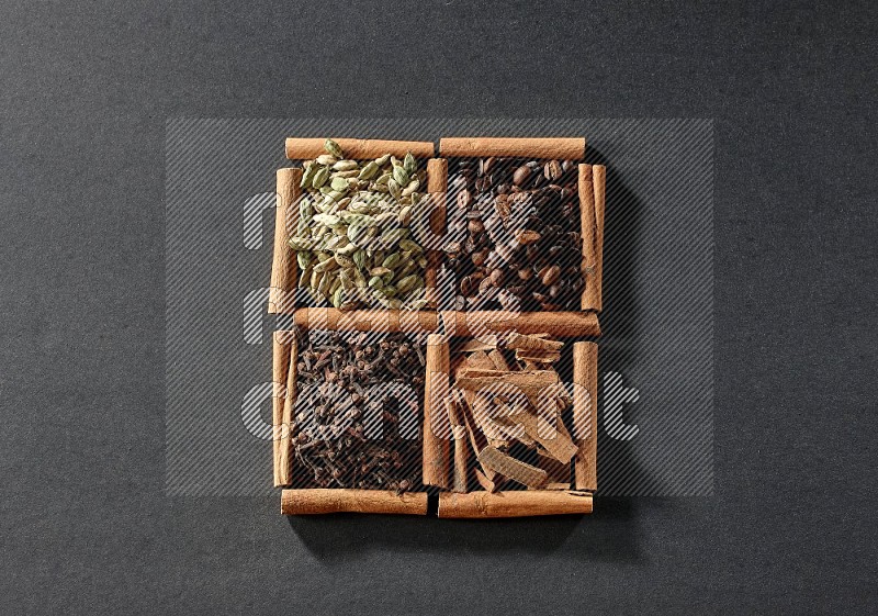 4 squares of cinnamon sticks full of coffee beans, cinnamon, cloves and cardamom on black flooring
