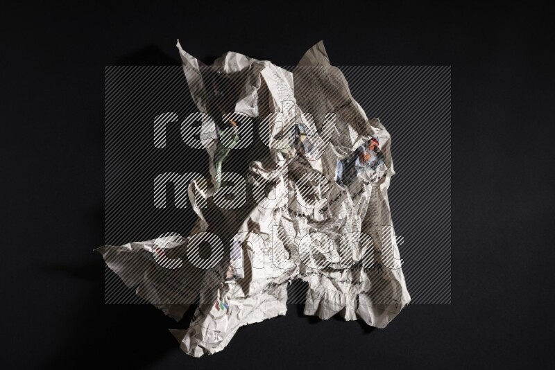 Crumpled newspaper sheet on black background