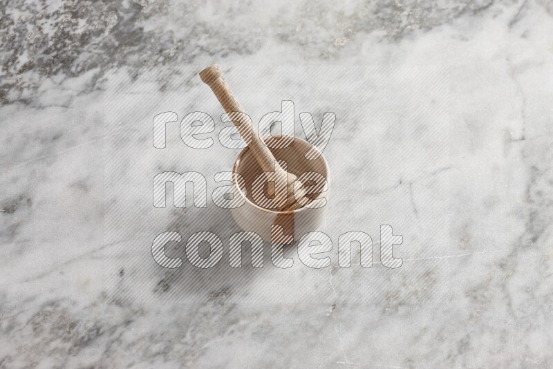 Beige pottery bowl with wooden honey dipper in it on grey marble background