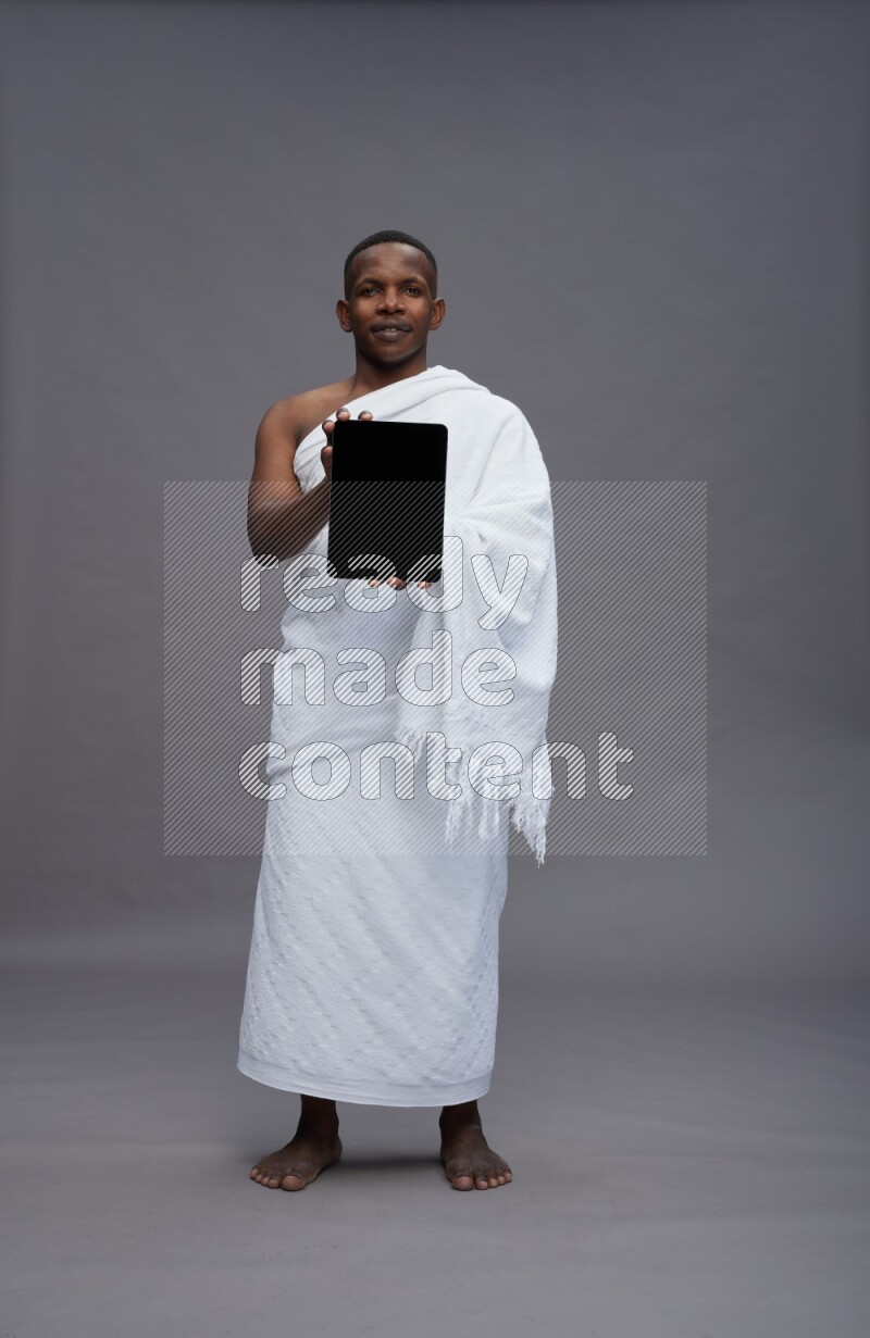 A man wearing Ehram Standing showing tablet to camera on gray background