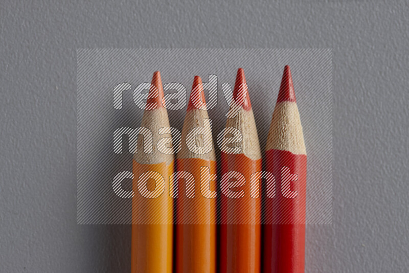 مجموعة من أقلام الرصاص الملونة مرتبة لتعرض تدرجا من الألوان البرتقالية علي خلفية رمادية