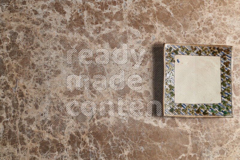 A decorative pottery plate on beige marble background