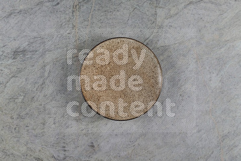 Top View Shot Of A Beige Pottery Plate On Grey Marble Flooring