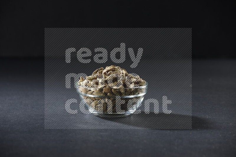 A glass bowl full of cardamom on black flooring