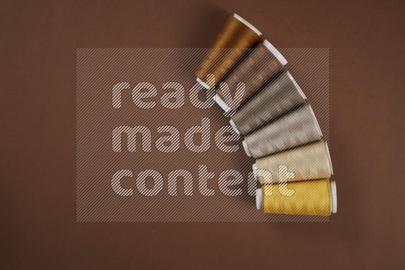 A yellow collection of sewing and tailoring tools arranged on a brown background