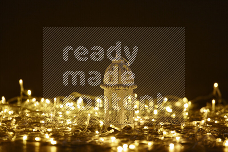 A traditional ramadan lantern surrounded by glowing fairy lights in a dark setup