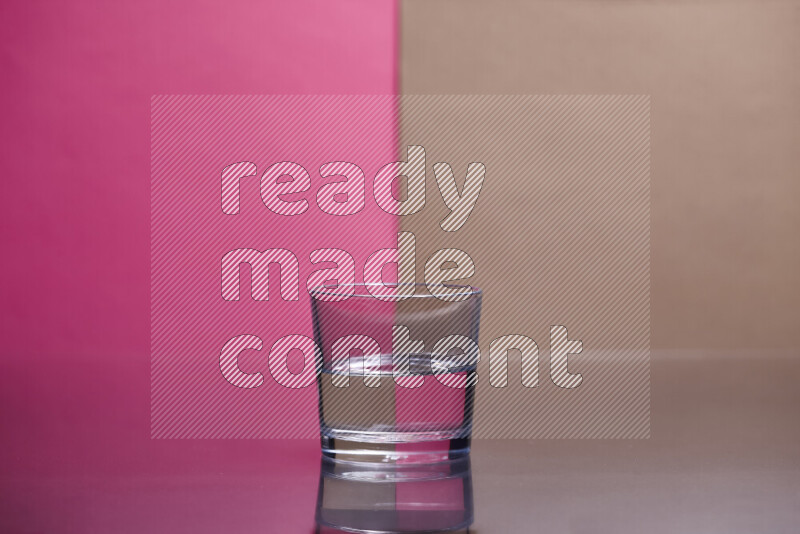 The image features a clear glassware filled with water, set against pink and beige background