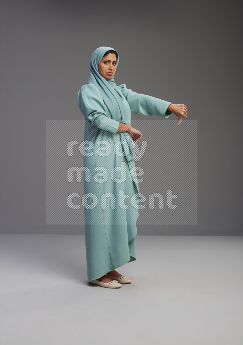 Saudi Woman wearing Abaya standing interacting with the camera on Gray background