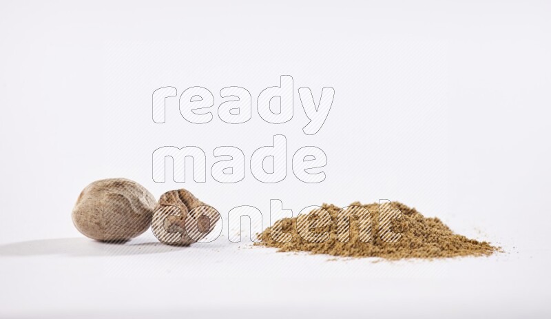 Nutmeg whole seeds with nutmeg powder beside it on a white flooring