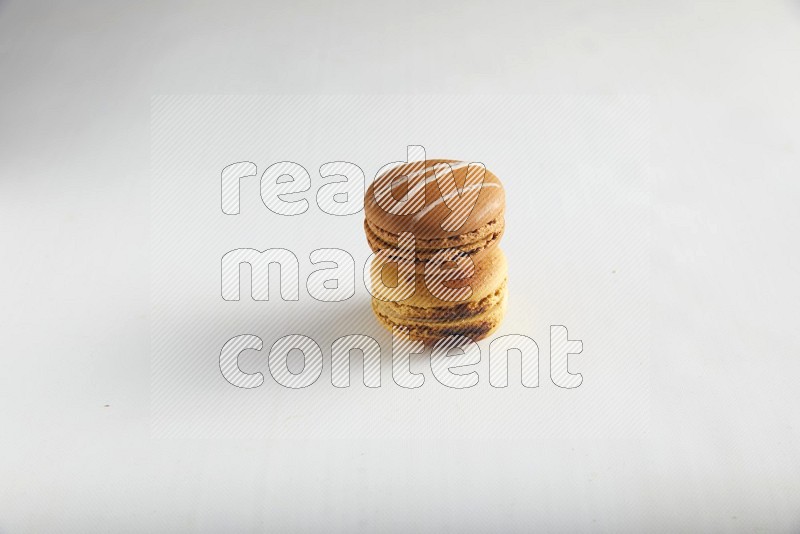 45º Shot of of two assorted Brown Irish Cream, and Yellow Crème Brulée macarons on white background