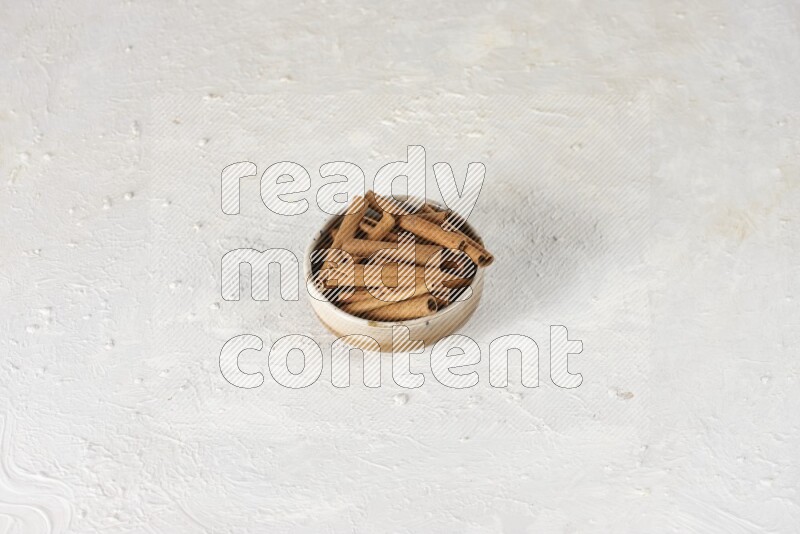 Cinnamon sticks in a ceramic bowl in different angles on white background