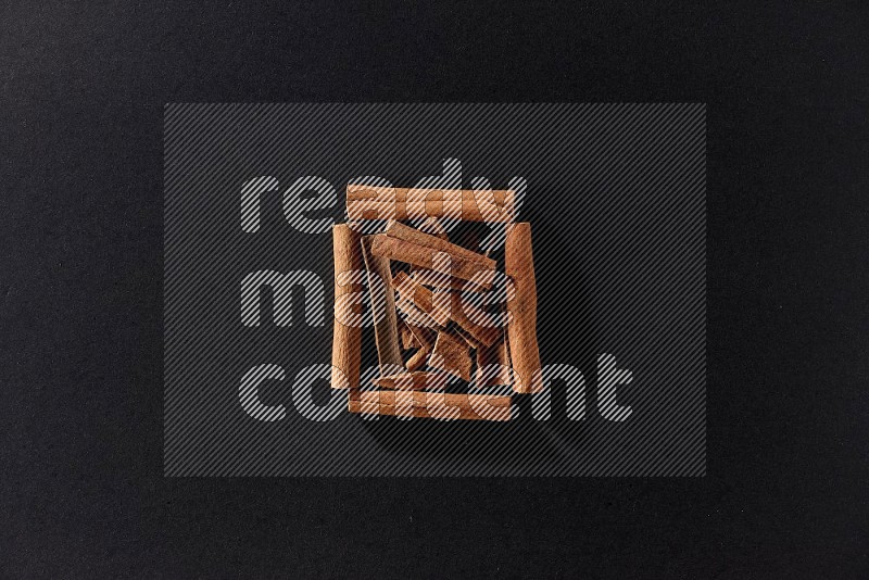 A single square of cinnamon sticks full of cinnamon on black flooring