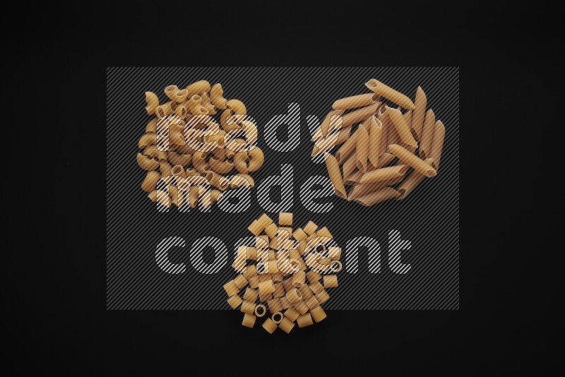 Different pasta types in bunches on black background