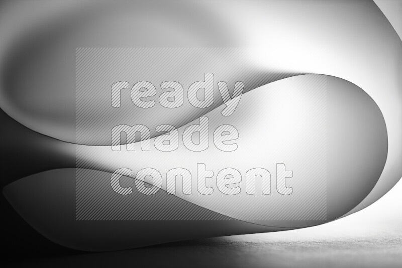 An abstract art piece displaying smooth curves in grey gradients created by colored light