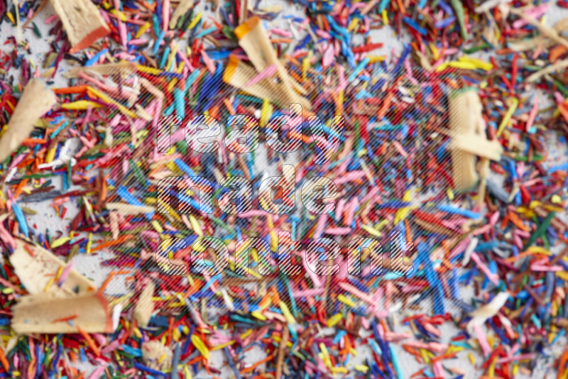 This image showcases a vibrant multicolored pencil shavings scattered on grey background