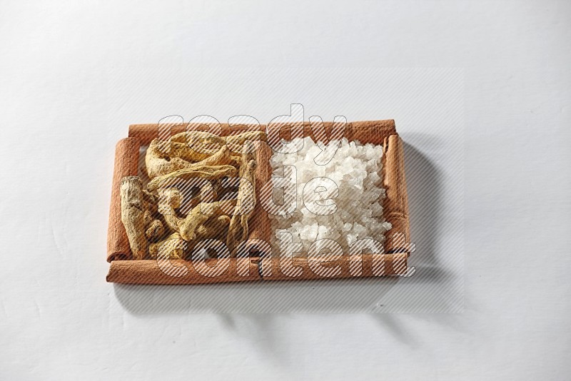 2 squares of cinnamon sticks full of turmeric fingers and white salt on white flooring