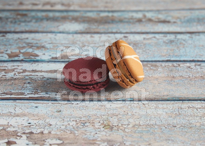 45º Shot of of two assorted Brown Irish Cream, and Red Cherry macarons  on light blue background