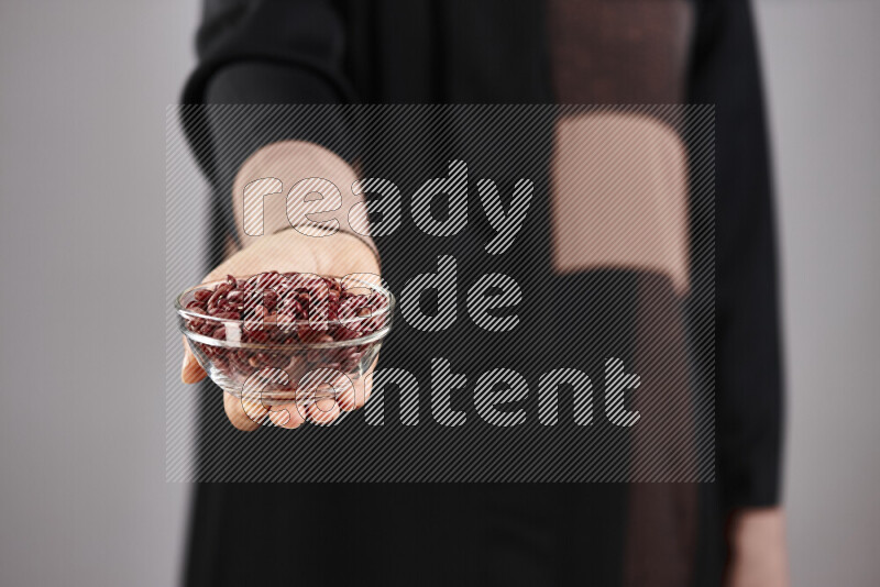 Woman in abaya holding different kinds of legumes in different positions