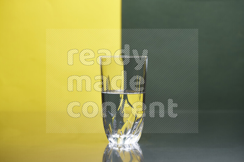 The image features a clear glassware filled with water, set against yellow and dark green background