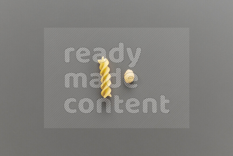 Shells pasta with other types of pasta on grey background