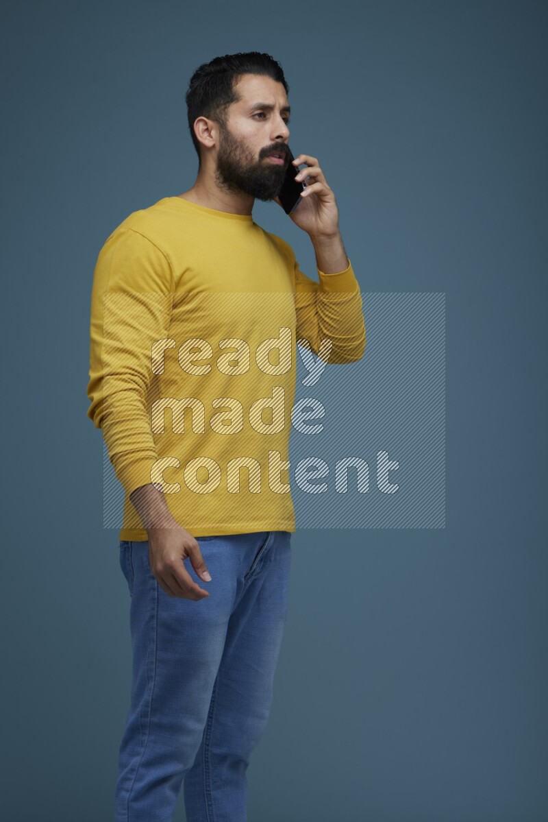 A man having a calling in a blue background wearing a yellow shirt