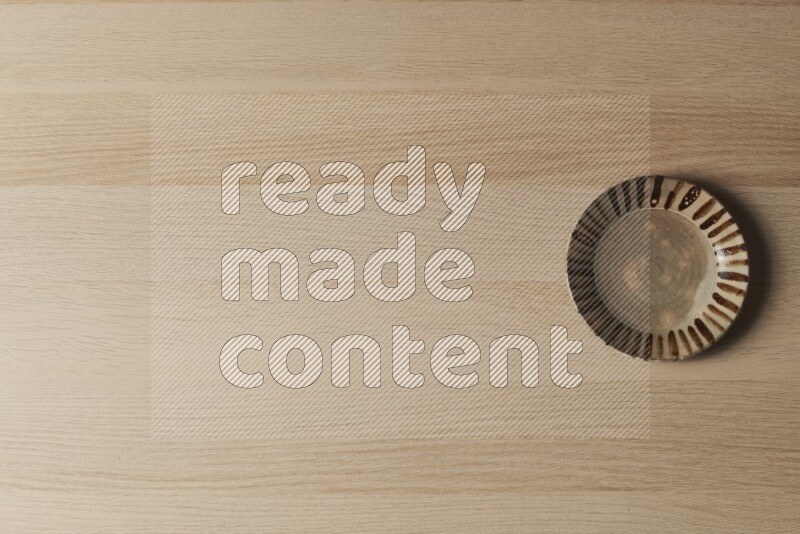 صحن فخاري متعدد الألوان على خلفية خشبية فاتحة