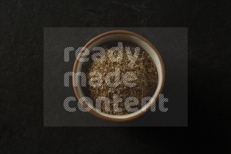 multi color round sauce bowl filled with herbs on grey textured countertop