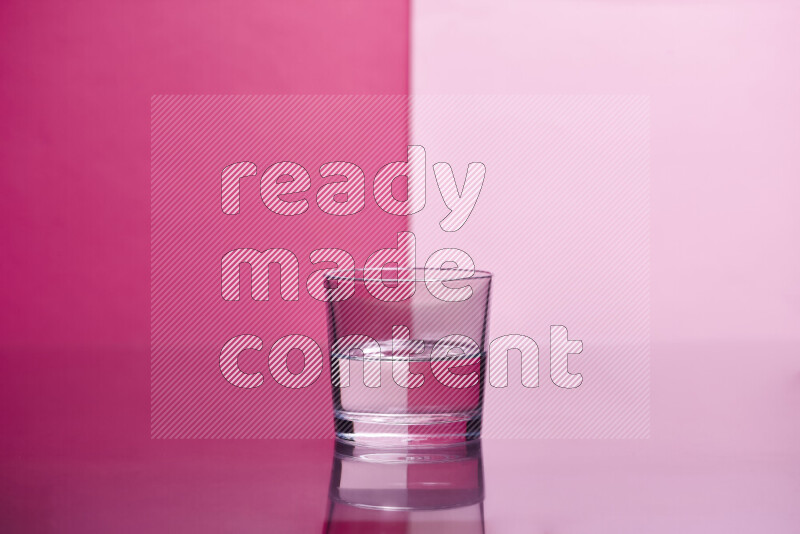 The image features a clear glassware filled with water, set against pink background