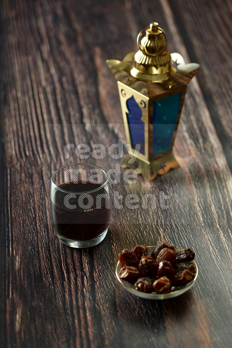 A golden lantern with drinks, dates, nuts, prayer beads and quran on brown wooden background