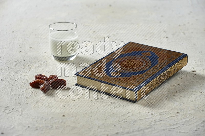 Quran with dates, prayer beads and different drinks all placed on textured white background