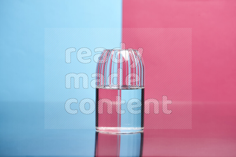 The image features a clear glassware filled with water, set against light blue and pink background