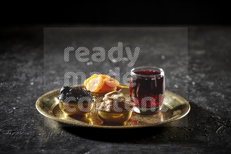 Dried fruits in metal bowls with Hibiscus on a tray in dark setup