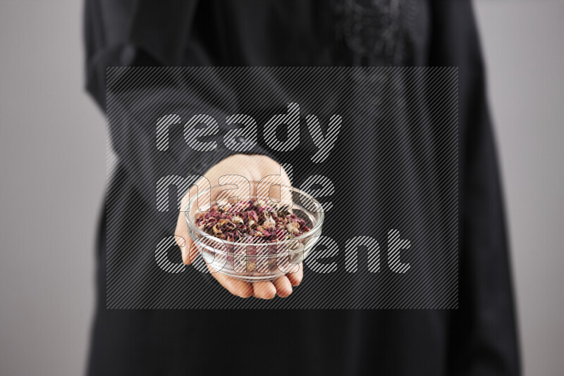 Woman in abaya holding different kinds of spices in different positions