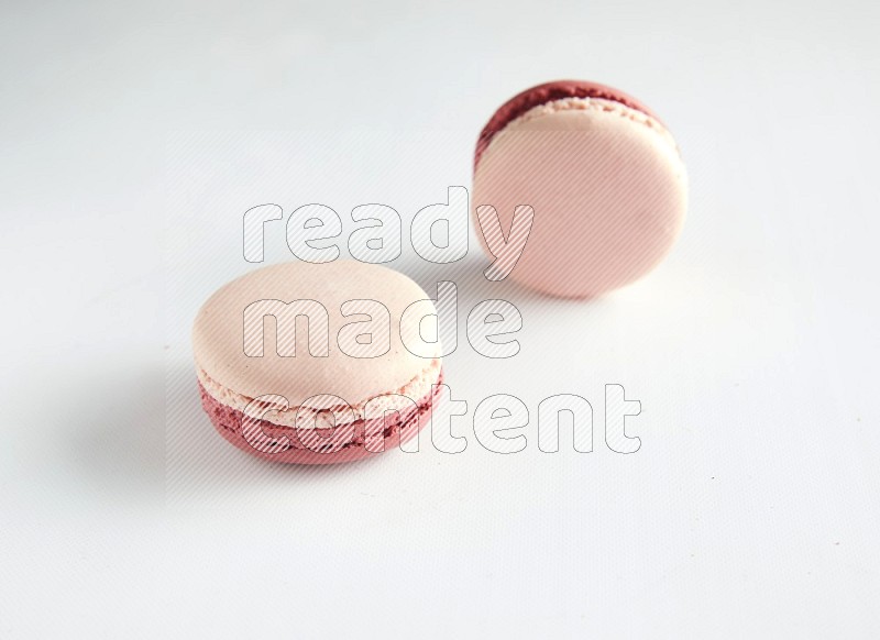 45º Shot of two Pink Litchi Raspberry macarons on white background