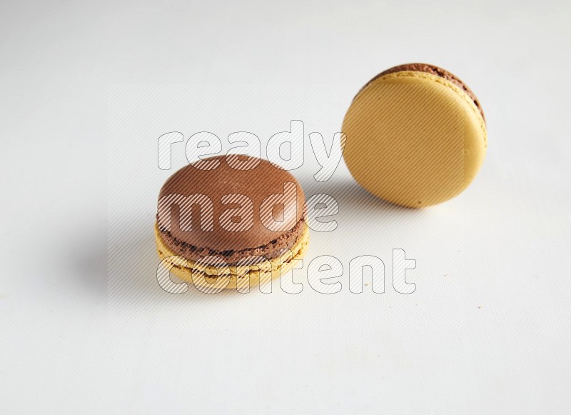 45º Shot of two Yellow and Brown Chai Latte macarons on white background