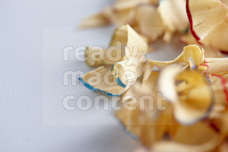 صورة مقربة تظهر كومة صغيرة من نشارة الأقلام ذات حواف ملونة متنوعة علي خلفية رمادية