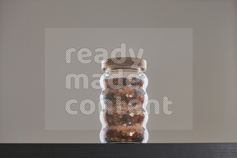 Sequins in a glass jar on black background