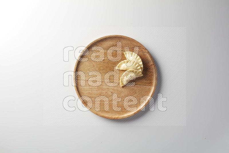 Three Sambosas on a wooden round plate on a white background