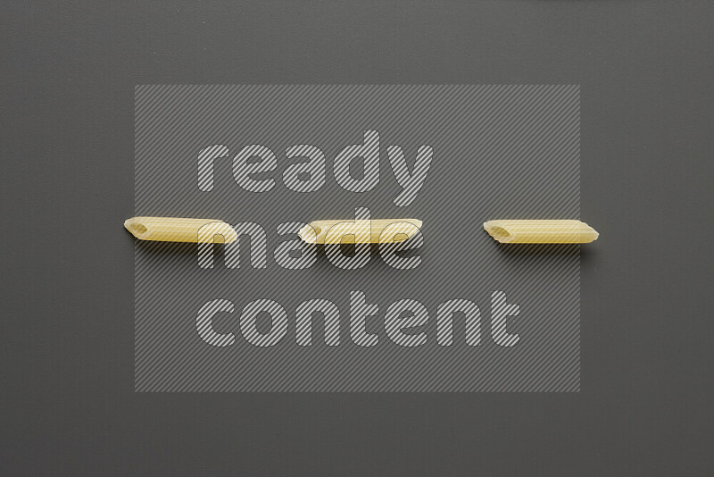 Mini penne pasta on grey background