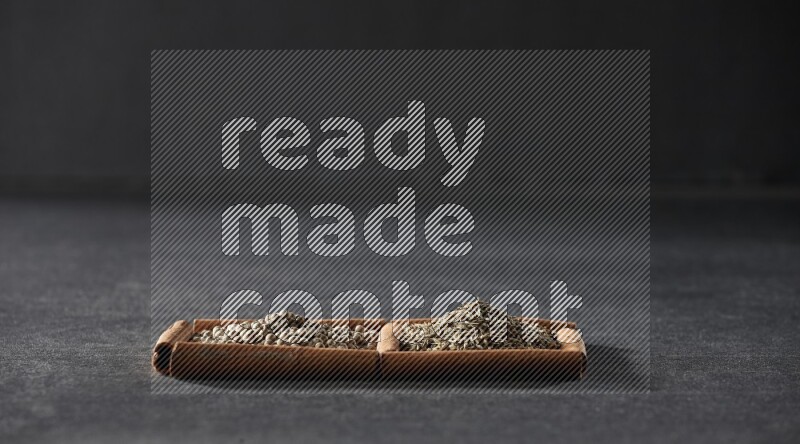 مربعان من أعواد القرفة ممتلئان بحبوب الفلفل الأبيض وحبوب الكمون علي خلفية سوداء