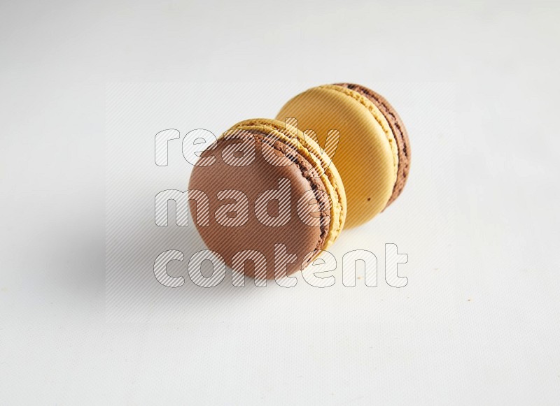 45º Shot of two Yellow and Brown Chai Latte macarons on white background